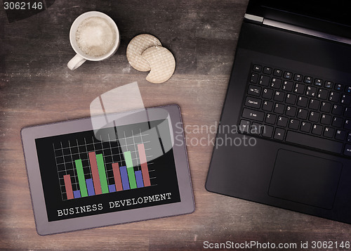 Image of Tablet touch computer gadget on wooden table, graph