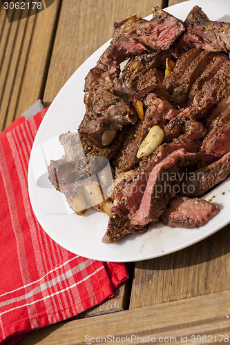 Image of Plate of Grilled Steak and Garlic with Red Napkin