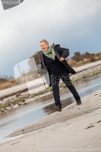 Image of Happy senior woman frolicking on the beach