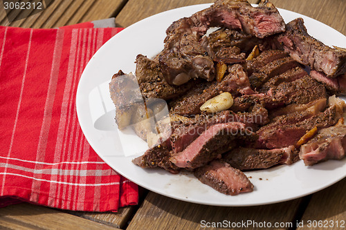 Image of Plate of Grilled Steak and Garlic with Red Napkin