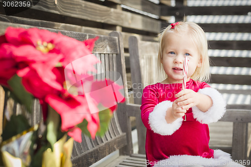Image of Adorable Little Girl Sitting On Bench with Her Candy Cane