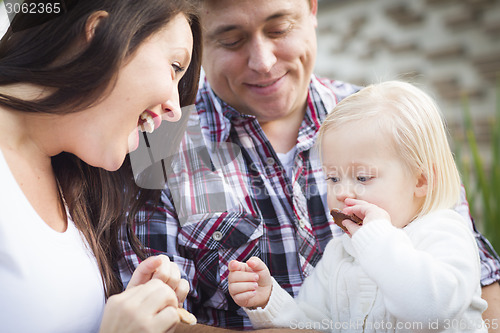 Image of Adorable Little Girl Eating a Cookie with Mommy and Daddy