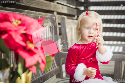 Image of Adorable Little Girl Sitting On Bench with Her Candy Cane