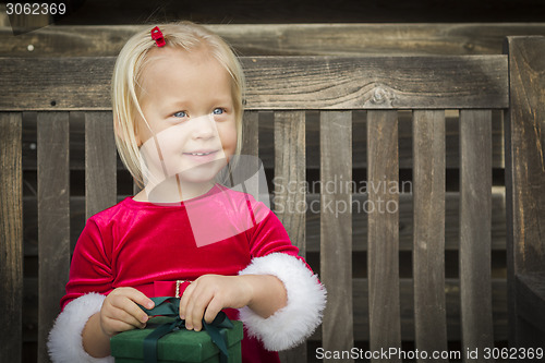 Image of Adorable Little Girl Unwrapping Her Gift on a Bench