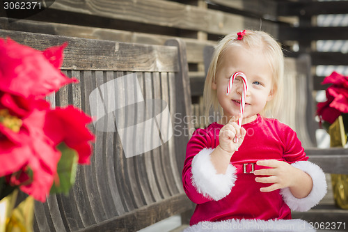 Image of Adorable Little Girl Sitting On Bench with Her Candy Cane