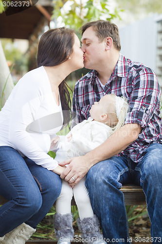 Image of Happy Pregnant Couple Kisses as Baby Girl Watches
