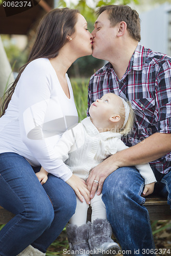 Image of Happy Pregnant Couple Kisses as Baby Girl Watches