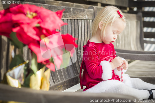 Image of Adorable Little Girl Sitting On Bench with Her Candy Cane