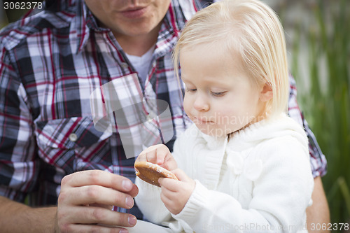 Image of Adorable Little Girl Eating a Cookie with Daddy