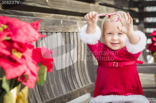 Image of Adorable Little Girl Sitting On Bench with Her Candy Cane