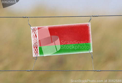 Image of Border fence - Old plastic sign with a flag