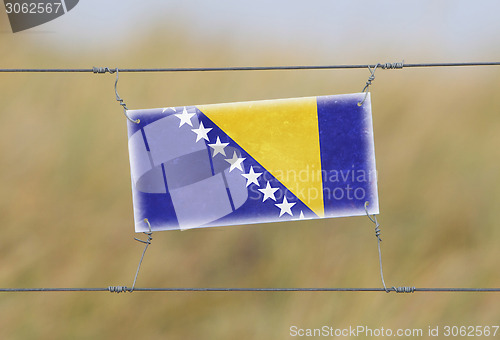 Image of Border fence - Old plastic sign with a flag