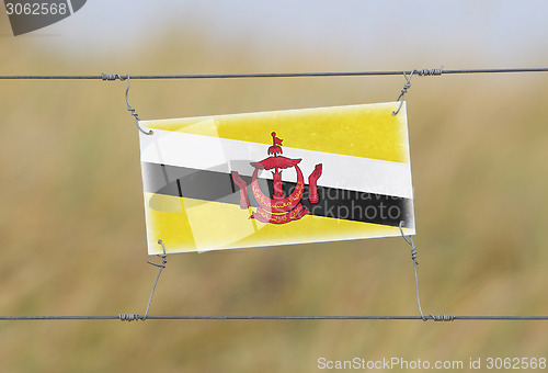 Image of Border fence - Old plastic sign with a flag