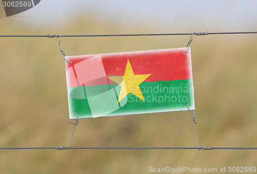 Image of Border fence - Old plastic sign with a flag