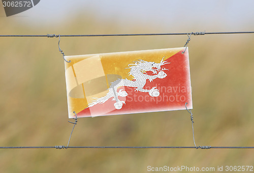 Image of Border fence - Old plastic sign with a flag