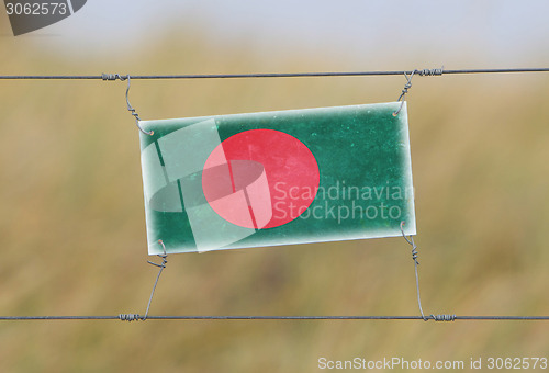 Image of Border fence - Old plastic sign with a flag