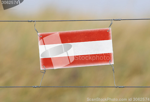 Image of Border fence - Old plastic sign with a flag