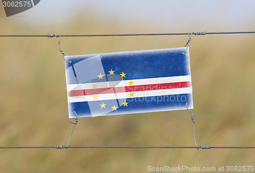 Image of Border fence - Old plastic sign with a flag