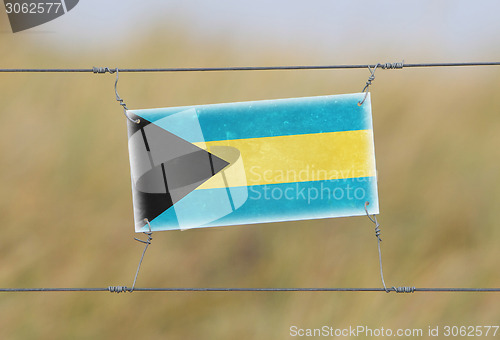 Image of Border fence - Old plastic sign with a flag