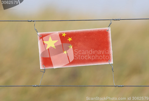 Image of Border fence - Old plastic sign with a flag