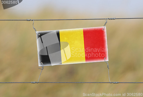 Image of Border fence - Old plastic sign with a flag