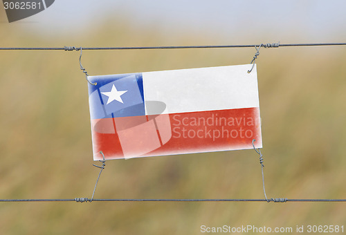 Image of Border fence - Old plastic sign with a flag