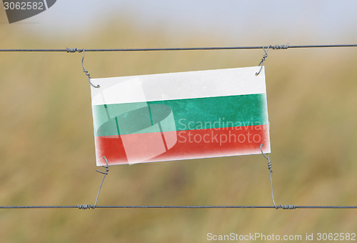 Image of Border fence - Old plastic sign with a flag