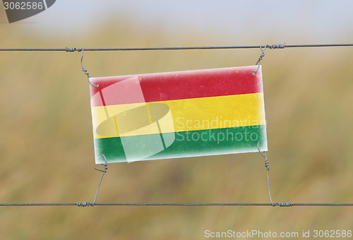 Image of Border fence - Old plastic sign with a flag