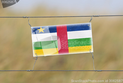 Image of Border fence - Old plastic sign with a flag