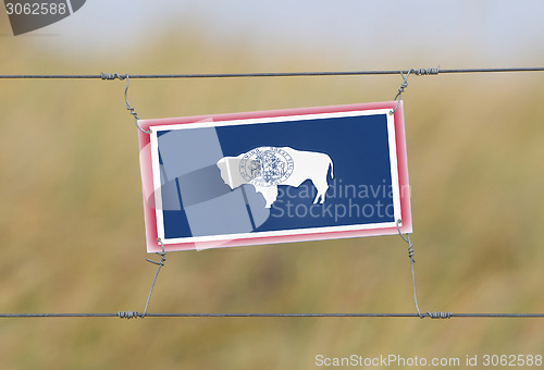 Image of Border fence - Old plastic sign with a flag