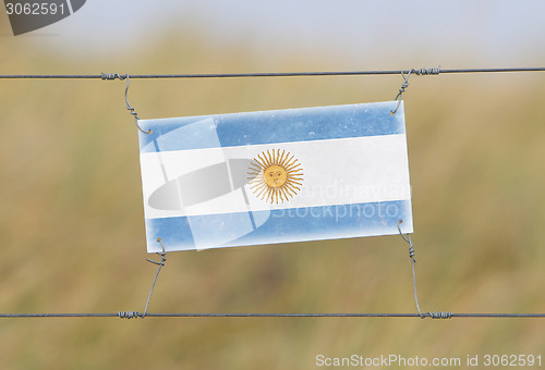 Image of Border fence - Old plastic sign with a flag