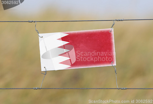 Image of Border fence - Old plastic sign with a flag