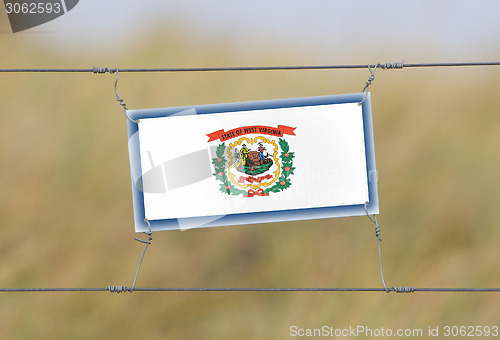 Image of Border fence - Old plastic sign with a flag