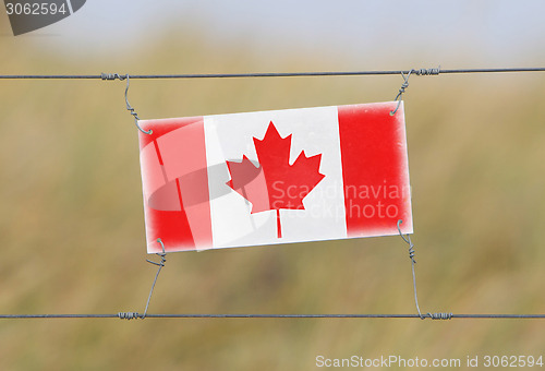 Image of Border fence - Old plastic sign with a flag