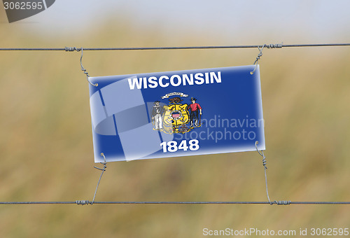 Image of Border fence - Old plastic sign with a flag