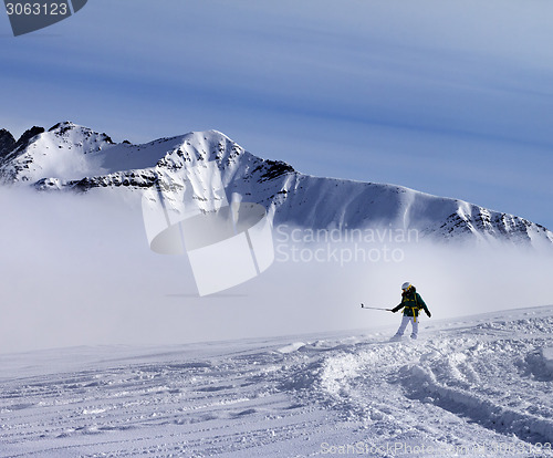 Image of Snowboarder downhill on off-piste slope with newly fallen snow