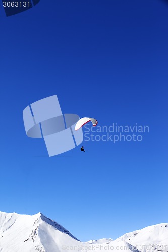 Image of Paraglider in snowy winter mountains at sun day