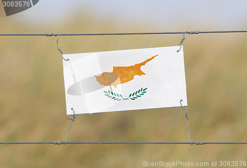 Image of Border fence - Old plastic sign with a flag