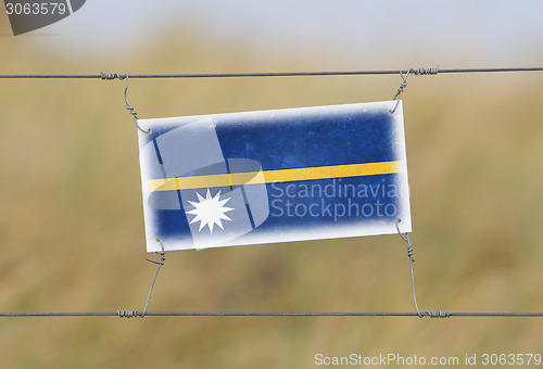 Image of Border fence - Old plastic sign with a flag