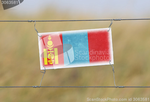 Image of Border fence - Old plastic sign with a flag