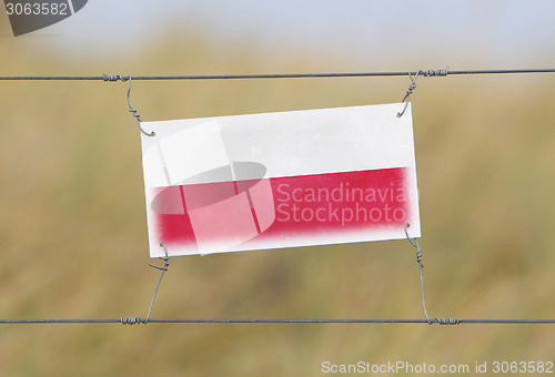 Image of Border fence - Old plastic sign with a flag