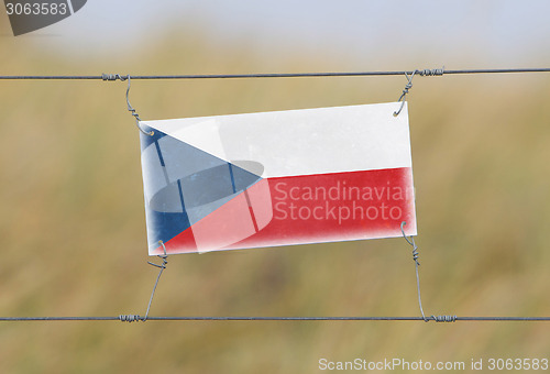 Image of Border fence - Old plastic sign with a flag