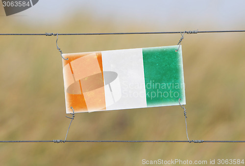 Image of Border fence - Old plastic sign with a flag