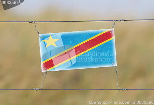 Image of Border fence - Old plastic sign with a flag