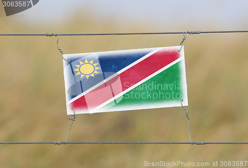 Image of Border fence - Old plastic sign with a flag