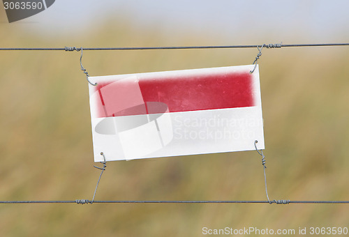 Image of Border fence - Old plastic sign with a flag