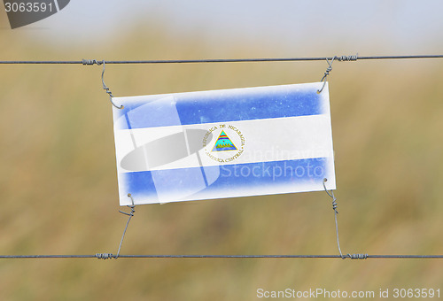 Image of Border fence - Old plastic sign with a flag