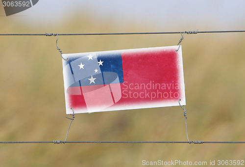 Image of Border fence - Old plastic sign with a flag