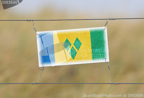 Image of Border fence - Old plastic sign with a flag