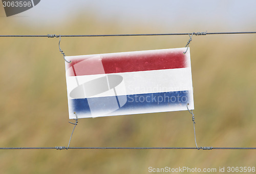 Image of Border fence - Old plastic sign with a flag